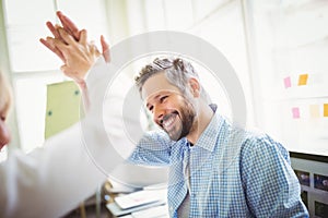 Happy coworkers giving high-five in creative office