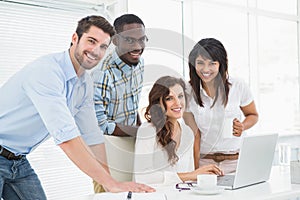 Happy coworkers working together with laptop