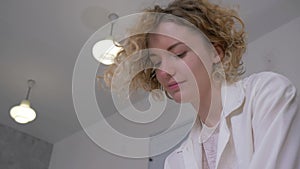 Happy craftsman woman with curly hair kneading clay and makes softer and pliable on worktable at art studio bottom view