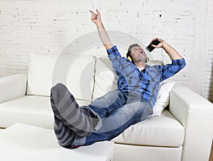 Happy crazy man on couch listening to music holding mobile phone as microphone