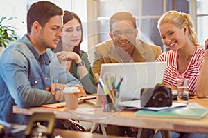 Happy creative business team using laptop in meeting