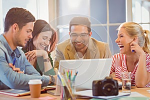 Happy creative business team using laptop in meeting