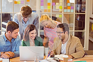 Happy creative business team using laptop in meeting