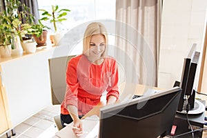 Happy creative female office worker with computers