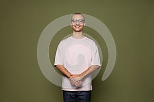 Happy creative man wearing t-shirt and glasses smiling standing on khaki green studio wall banner background