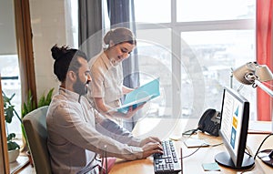 Happy creative team with computer in office