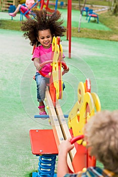 happy curly african american child riding on rocking horse with boy