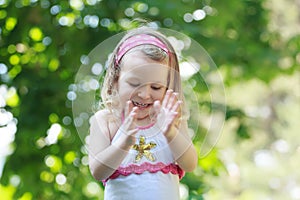 Happy curly toddler girl clapping with her palms