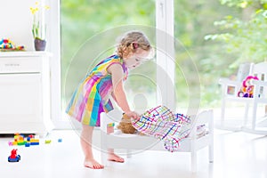 Happy curly toddler girl playing with her teddy bear