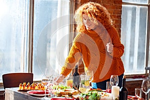 Happy curly woman serving festive holiday table for feasting family dinner