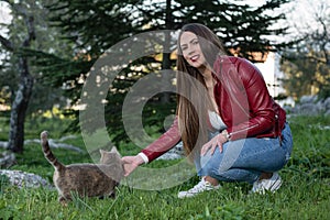 Happy curvy girl stroking a cat in nature