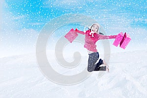 Happy customer jumping with bags in winter snow