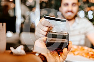 Happy customer paying for lunch using new, modern contactless technology with credit card