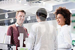 Happy customer talking with two helpful pharmacists in a contemporary drugstore