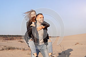 Happy and cute adorable adult couple of millennial hipsters, man with woman girlfriend on piggy back, have fun play