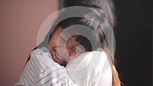 Happy cute affectionate adopted little Asian kid girl hugging foster care parent mother.