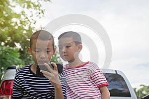 Happy cute Asian boy play game with smartphone sit on the park