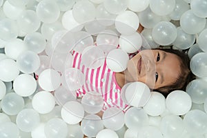 Happy cute asian child girl having fun to play with white plastic balls