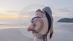Happy cute baby boy with his mother on the beach. Summertime with baby is a quality time for Asian mommy.  Mother and baby on the