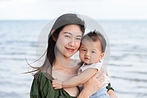 Happy cute baby boy with his mother on the beach. Summertime with baby is a quality time for Asian mommy.  Mother and baby on the