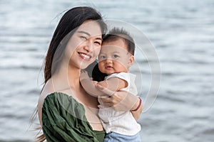 Happy cute baby boy with his mother on the beach. Summertime with baby is a quality time for Asian mommy.  Mother and baby on the