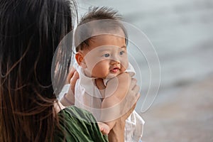 Happy cute baby boy with his mother on the beach. Summertime with baby is a quality time for Asian mommy.  Mother and baby on the