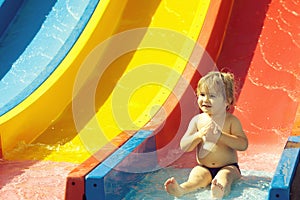 Happy cute baby boy rides from waterslide