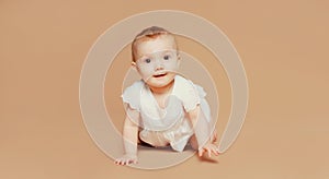 Happy cute baby crawling on the floor on brown studio background