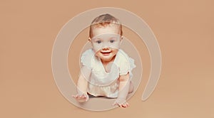 Happy cute baby crawling on the floor on brown studio background