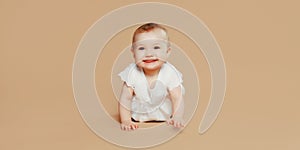 Happy cute baby crawling on the floor on brown studio background
