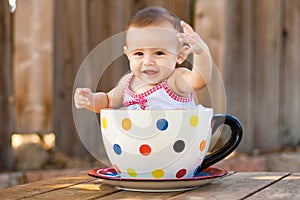 Happy and cute baby girl in giant teacup