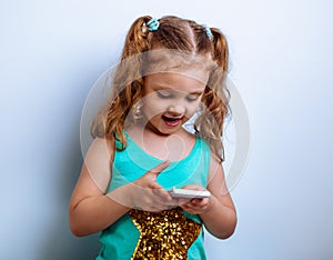 Happy cute baby girl with happy face answering with smile on sms on mobile phone her baby boy on blue background. Closeup