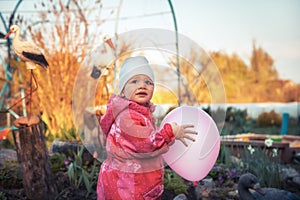 Happy cute baby girl playing with balloon outdoors on backyard in countryside