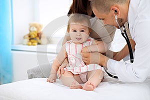 Happy cute baby at health exam at doctor`s office. Medicine and health care concept