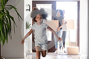 African parents entering new home with kid running in hallway