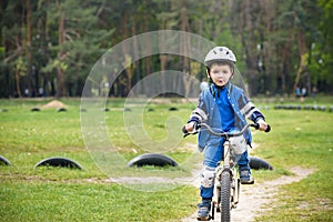 Happy cute blond kid boy having fun his first bike on sunny summer day