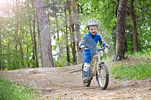 Happy cute blond kid boy having fun his first bike on sunny summer day, outdoors. child making sports. Active leisure for childre