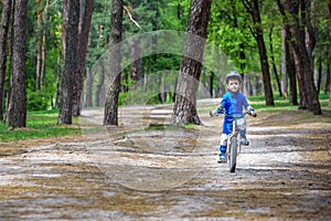 Happy cute blond kid boy having fun his first bike on sunny summer day, outdoors. Happy child making sports. Active leisure for c