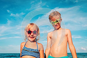 Happy cute boy and girl play with water on beach