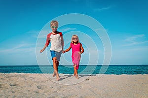 Happy cute boy and girl running on beach