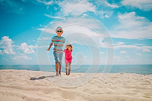 Happy cute boy and girl running on beach, kids play at sea