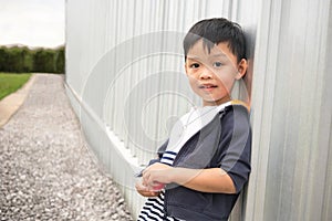 Happy cute boy leaning wall of building and perspective way background