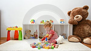 Happy cute child boy having fun playing with colorful wooden blocks on the floor, at home. Indoor activity for kids