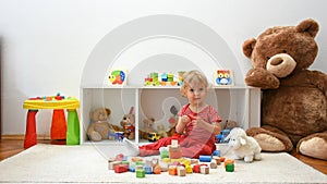 Happy cute child boy having fun playing with colorful wooden blocks on the floor, at home. Indoor activity for kids