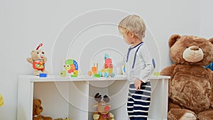 Happy cute child boy having fun playing with colorful wooden toys, at home. Indoor activity for kids