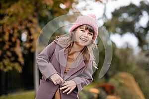 Happy cute child girl 4-5 year old wear knit wool hat and jacket over nature backggound outdoors.
