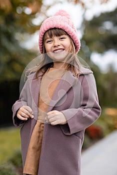 Happy cute child girl 4-5 year old wear knit wool hat and jacket over nature backggound outdoors.