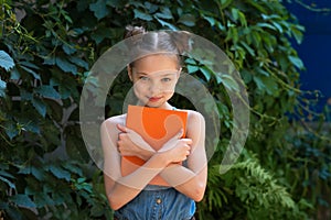 Happy cute child girl in school uniform holding books