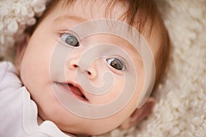 Happy, cute and closeup of baby on blanket playing for child development and curious face. Smile, sweet and young girl