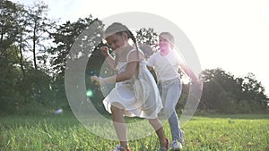 Happy cute family of girls playing catch-up on the field in the park. Sister`s kid dream and run in the park. Kid girls